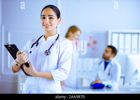 Weibliche arabische Arzt, der vor ihr steht Team im Krankenhaus Stockfoto