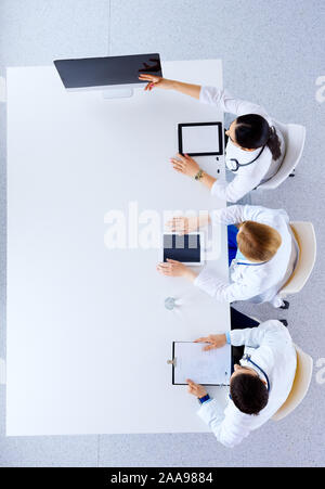 Flach, Ansicht von oben. Gruppe von Ärzten mit Tabletten und Computer im Krankenhaus Diskussion und zeigen etwas auf dem Bildschirm - Medizin, Gesundheitswesen und Cardigan Stockfoto