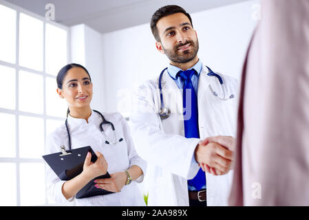 Junge arabische Arzt schüttelt Hände mit einem Patienten in einem Krankenhaus Stockfoto