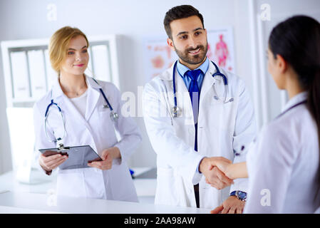 Junger Arzt schüttelt Hände mit einer Krankenschwester in einem Krankenhaus. Vor dem Hintergrund des menschlichen Körpers Stockfoto