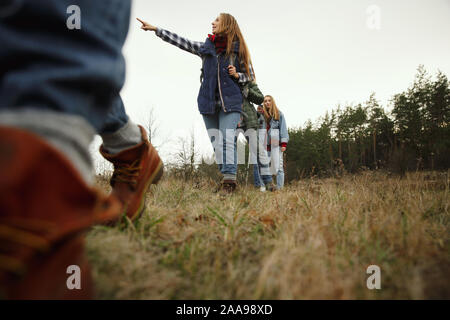 Eine Gruppe von Freunden auf einem Campingplatz oder Wanderung im Herbst Tag. Männer und Frauen mit touristischen Rucksäcke gehen durch den Wald, Reden, Laughting. Freizeit, Freundschaft, Wochenende. Stockfoto