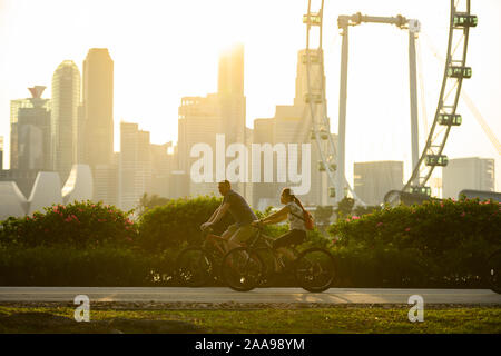 (Selektive Fokus) Menschen Radfahren in einem öffentlichen Park mit Blick auf die Skyline von Singapur in den Hintergrund. Stockfoto