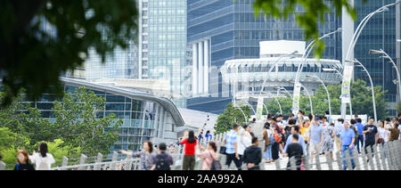 (Fokus auf den Hintergrund) Defokussierten Masse von Einheimischen und Touristen zu Fuß auf einer Brücke in Singapur. Stockfoto