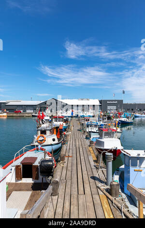 Kleine Fischerboote durch eine hölzerne Anlegestelle im Hafen von Hirtshals, Dänemark Stockfoto