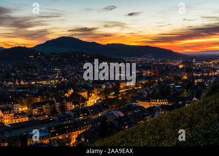 Deutschland, Freiburg im Breisgau City Skyline, Stadtbild und Häuser bei Nacht beleuchteten, von magischen Roten sonnenuntergang himmel eingerichtet, Luftaufnahme über Dächer Stockfoto