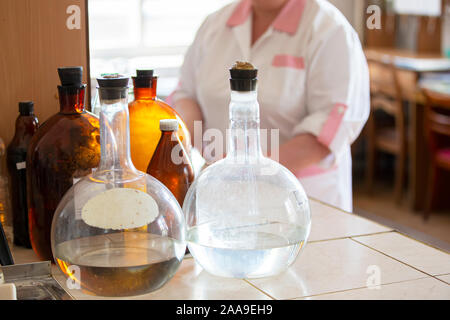 Glaskolben auf einem Labortisch. Retro Apotheke Container auf dem Hintergrund der Laboratory Assistant Stockfoto