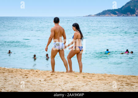 Ein Brasilianisches Paar auf dem Sand Grumari Strand in Rio de Janeiro, Brasilien bummeln. Stockfoto