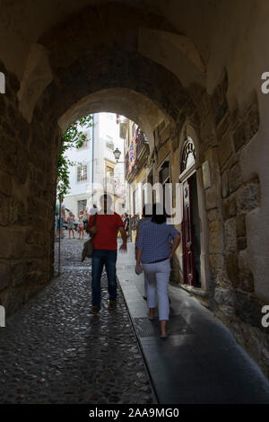 Die Menschen gehen durch die almedina Torbogen in der Altstadt von Coimbra Portugal Stockfoto