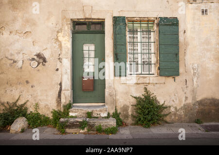 Haus vorne mit grün lackierten traditionellen Fensterläden aus Holz und Gardinen auf einer Straße in Arles, Südfrankreich. Stockfoto