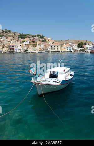 Boot am Hafen von Simi Dodekanes Griechenland. Weiße Boot im Hafen Insel Symi mit bunten Gebäuden und blaues Meer Stockfoto