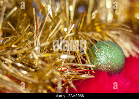 Verschwommen abstrakte Weihnachten Hintergrund des goldenen Lametta und Green Christmas Ball. Weihnachten Lametta glitzert im Licht. Flauschig roten Fell mit langen Stapel Stockfoto