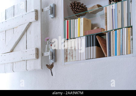 Kleine eingerichtete Bücherregal mit weißen Holzmöbeln schäbig Verschluss in einer weißen Wand Stockfoto