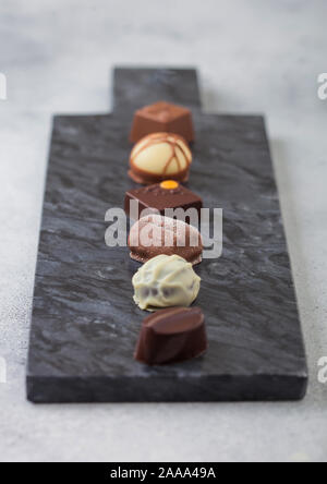 Luxus Pralinen Auswahl auf schwarzem Marmor. Weißer, dunkler und Milchschokolade Sortiment. Ansicht von oben Stockfoto