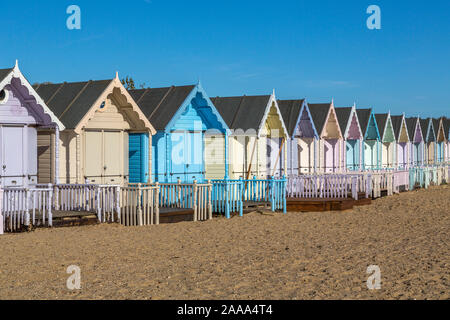 Eine Reihe von pastellfarbenen Holzhütten am West Mersea. Mersea Island, Essex, Vereinigtes Königreich. Stockfoto