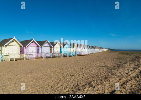 Eine Reihe von pastellfarbenen Holzhütten am West Mersea. Mersea Island, Essex, Vereinigtes Königreich. Stockfoto