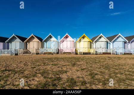 Eine Reihe von pastellfarbenen Holzhütten am West Mersea. Mersea Island, Essex, Vereinigtes Königreich. Stockfoto