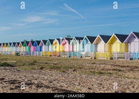 Eine Reihe von pastellfarbenen Holzhütten am West Mersea. Mersea Island, Essex, Vereinigtes Königreich.