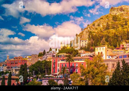 Panoramablick auf den malerischen Stadt Taormina, Sizilien, Italien. Häuser und Resorts auf dem Hügel mit schöner Landschaft mit Bäumen, Felsen und Wolken. Stockfoto