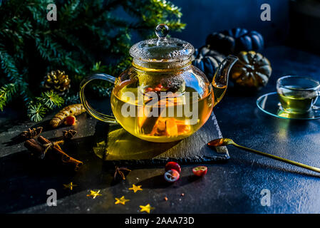 Tee in eine Kanne. Eine Infusion von Kurkuma, Ingwer und Cranberry. Weihnachten herbst Atmosphäre. Schwarzen Hintergrund. Stockfoto