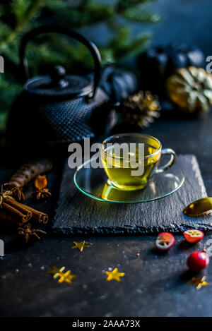 Tee in eine Kanne. Eine Infusion von Kurkuma, Ingwer und Cranberry. Weihnachten herbst Atmosphäre. Schwarzen Hintergrund. Stockfoto