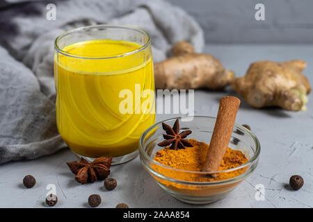 Goldene Milch mit Gewürzen. Gelbwurz, Nelken, schwarzer Pfeffer und einem Tropfen Pflanzenöl. Traditionelle indische trinken. Auf einem hellen Hintergrund. Stockfoto