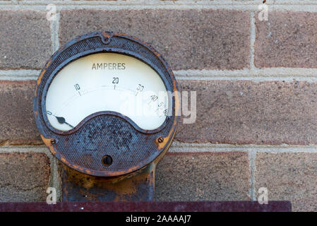 Ein Rost antik a meter Ampere angezeigt mit einer Nadel montiert draußen auf einer Mauer Stockfoto