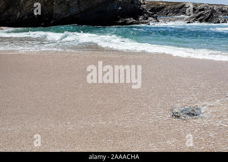 Die Wellen am Strand, die Wellen am Strand, einsame Stein im Sand in den Wellen Surf Zone. Stockfoto