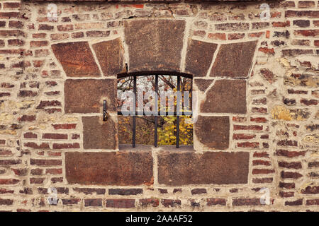 Detail der Öffnen/Schlupfloch mit rostigem Eisen umrahmten Gitter mit Steinblöcken in einer alten Backstein / Mauerwerk Befestigungsmauer von Vyšehrad, Prag Stockfoto