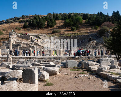 Besucher in ein Amphitheater und Ruinen in Ephesus, Türkei in einen Hang gebaut. Steinblöcke stehen im Vordergrund. Stockfoto