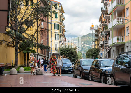 Italienische Frauen mit bunten Drucken kleider Spaziergang entlang einer Straße mit Wohnhäusern in der ligurischen Stadt Ventimiglia, Italien, an der italienischen Riviera. Stockfoto