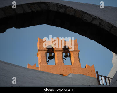 Der Sonnenbeschienenen Glockenturm und zwei Glocken unter einem gemauerten Bogen im Griechisch-orthodoxe Kloster des Hl. Johannes des Theologen auf Patmos Griechenland gesehen. Stockfoto