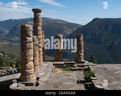 Sechs steinerne Säulen verbleibende am Tempel von Apollo in Delphi mit bewaldeten Bergen und Bar-lounge im Hintergrund. Stockfoto