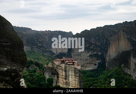 Das Kloster Roussanou erbaut auf einem Felsvorsprung durch graue Klippen und bedecktem Himmel umgeben. In Meteora, Griechenland fotografiert. Stockfoto
