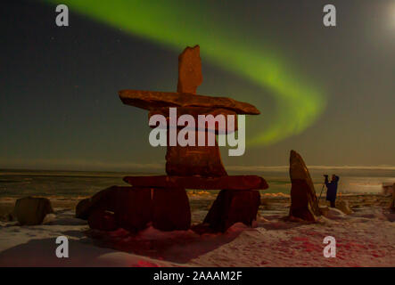 Touristen fotografieren Nordlichter über native inukshuk Rock Turm am Ufer des Hudson Bay bei Churchill, Kanada. Stockfoto