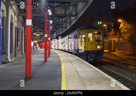 Arriva Northern Rail Class 319 elektrische Zug in Stockport Bahnhof auf einer dunklen Nacht mit einem stoppen Zug nach Crewe Stockfoto