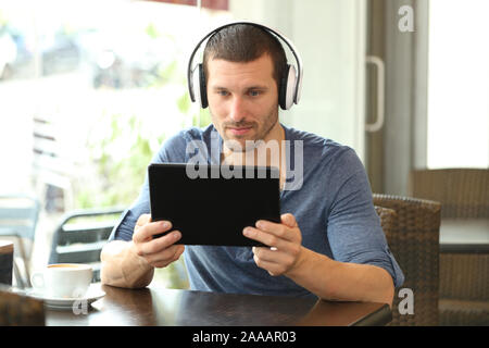 Ernster Mann mit Kopfhörern über einen Tablet-PC in einem Café sitzen Stockfoto