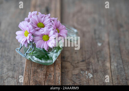 Rosa Astern in ein kleines Glas Vase von oben auf einem rustikalen Holzmöbeln schäbig Stockfoto