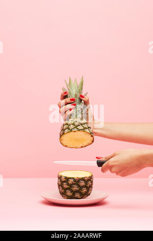 Die schöne Frau, die Hand mit dem Messer schneiden eine Ananas. Stockfoto