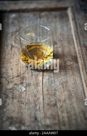 Whisky Glas mit golden schimmernden Single malt auf einem alten schäbigen verwendet Holztisch, von oben Stockfoto