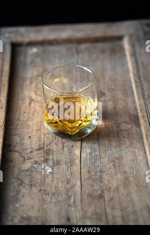 Whisky Glas mit golden schimmernden Single malt auf einem alten schäbigen verwendet Holztisch, von oben Stockfoto