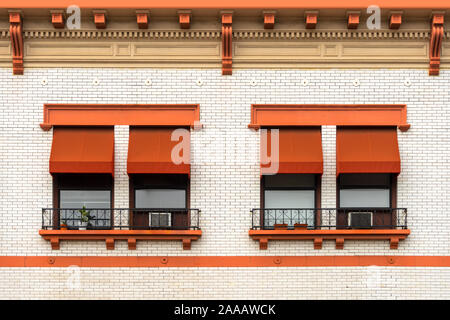 Orange Fenster Markisen auf ein weißes Ziegelgebäude Stockfoto