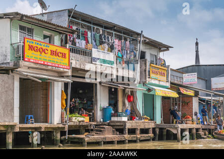 Cai, Mekong Delta, Vietnam - März 13, 2019: Entlang der Kinh 28 Kanal. Gehäuse mit Trocknen von Wäsche über der Reihe Einzelhandel Gastronomie an Kunden comin Stockfoto