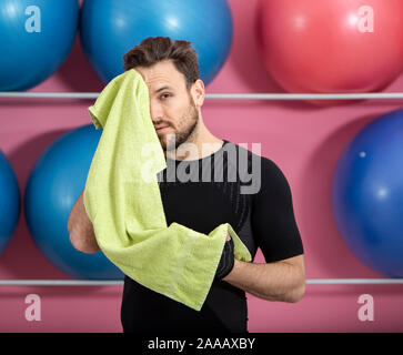 Porträt einer passen müde Mann sein Gesicht wischen mit einem Handtuch in der Turnhalle während der Ausbildung Stockfoto