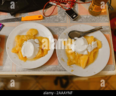 Mango Obst mit Joghurt und Löffel auf dem Tisch Stockfoto