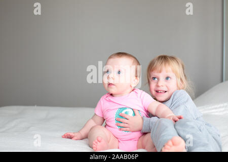 Nahaufnahme, Porträt von zwei Schwestern, 3 Jahre alt Blond Kleinkind Mädchen und 8 Monate altes Baby, Schwestern, beste Freunde, Happy Family Konzept Stockfoto