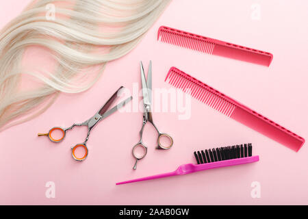 Scheren, Kämme und Accessoires anderer Friseur und Ausrichtung des blonden Haares auf rosa Hintergrund. Flach mit Platz für Text. Friseur service Stockfoto