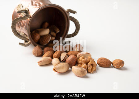 Mandeln, Haselnüsse, Pecan Nüsse, Pistazien auf eine weiße Fläche in einem alten Vintage kleine Schaufel Stockfoto