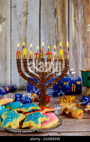 Hanukkah Kerzen, jüdischen Feiertagen traditionellen Kandelaber, Donuts und Holz- dreidels Kreisel. Stockfoto