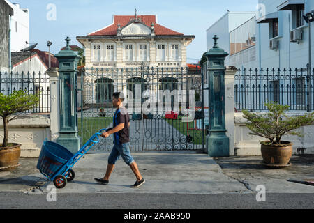 Ein Markt Porter mit seiner Katze übergibt Thai Hua Museum, eine ehemalige chinesische Schule, in Krabi Road in der Nähe der Altstadt von Phuket, Phuket, Thailand Stockfoto