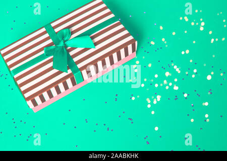 Geschenk gestreiften Feld mit einem roten Satinschleife und mit vielen kleinen Stars auf dem roten Hintergrund. Stockfoto